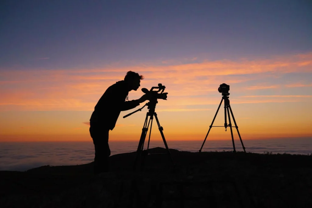 a man filming on a hill