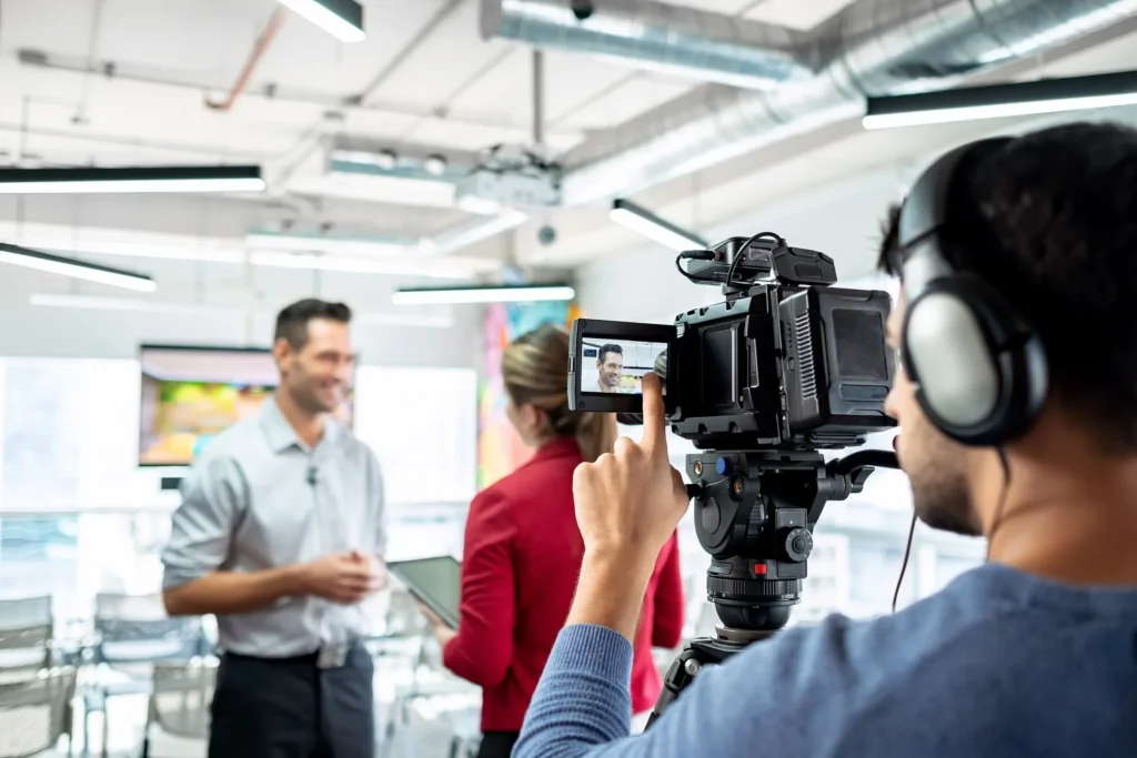 a man filming two people in a room